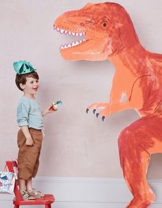 a little boy standing next to a giant dinosaur