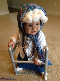 a baby sitting on top of a metal chair wearing a hat and eyeglasses