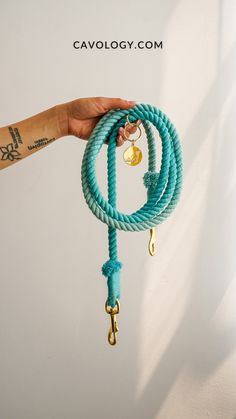 a hand holding a blue rope with gold hooks