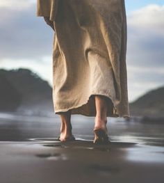 a person standing on the beach with their feet in the sand