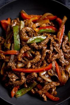 a black plate topped with meat and peppers