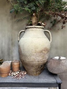 a large vase sitting on top of a wooden table next to two small pots filled with plants