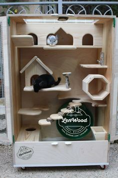 a black cat laying inside of a wooden toy house