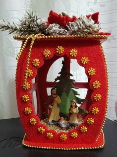 a red christmas decoration with two people and a tree in the center on a table