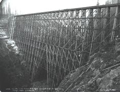 an old black and white photo of a bridge that is going over a hill side