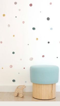 a blue stool sitting in front of a wall with polka dot decals on it