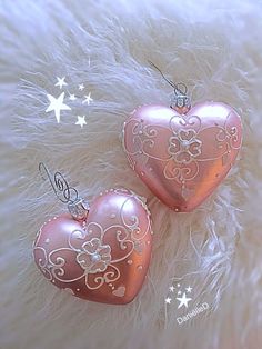 two pink heart shaped ornaments sitting on top of a furry surface