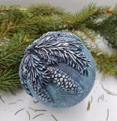 a blue ornament sitting on top of a pine tree