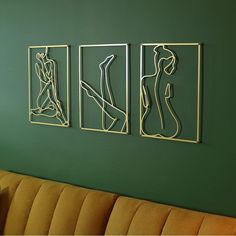 three metal art pieces on the wall above a couch in a living room with green walls