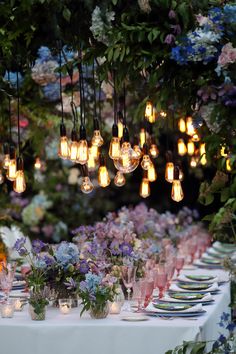 a long table with many lights hanging from it's ceiling and plates on the table