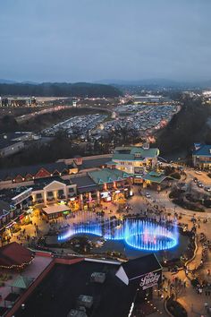 an aerial view of a city at night with lights on the buildings and people walking around