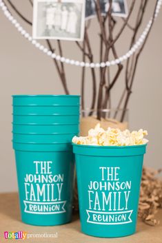 two blue cups filled with popcorn sitting on top of a table next to a tree