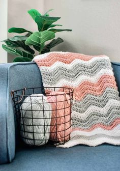 a crocheted blanket sitting on top of a blue couch next to a potted plant