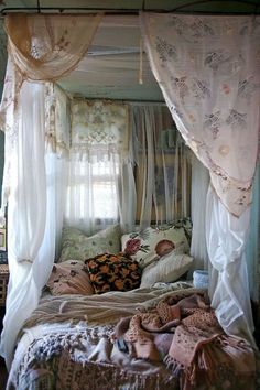 a canopy bed with curtains over it and pillows on the bottom floor in a bedroom