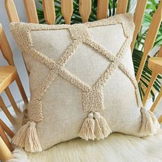 a pillow with tassels on it sitting on a chair