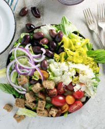 a salad with olives, lettuce, tomatoes and croutons