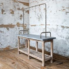 an old wooden table with two metal bars on it's legs and a shelf underneath