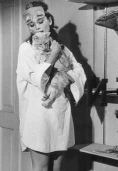 a woman with makeup on her face holding a cat