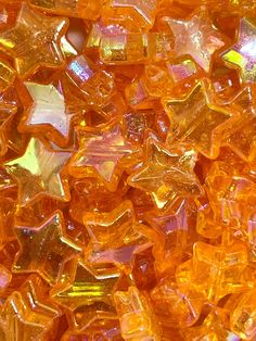 close up view of yellow and orange colored glass beads with small stars on them, as well as the background