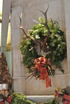 two wreaths with antlers and bows are hanging on the wall next to each other