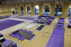 an empty gym with purple benches and windows