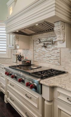 a stove top oven sitting inside of a kitchen next to white cabinets and counter tops