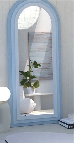 a blue arched mirror sitting on top of a table next to a vase with a plant in it