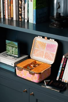 an open suitcase sitting on top of a book shelf next to a bookshelf