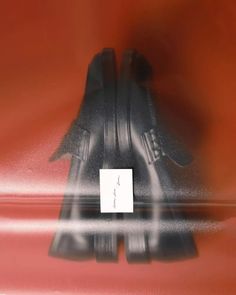 a pair of black shoes sitting on top of a red surface