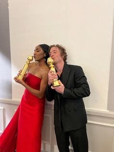 two people standing next to each other holding oscars in front of their faces and posing for the camera