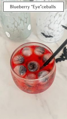 blueberry eyeballs in a glass with ice and black straws on the rim