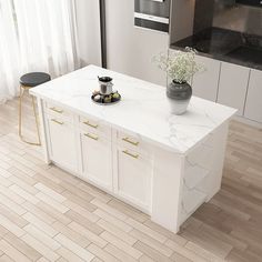 a white kitchen island with marble top and gold handles, in front of a stove