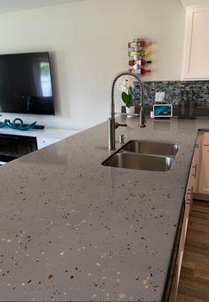 a kitchen counter with a sink and a television in the backgroung area