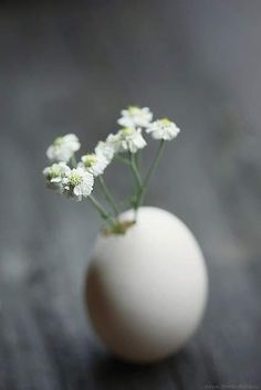 a white vase with flowers in it on a table