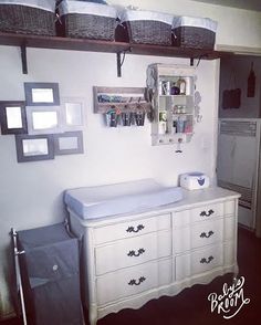 a baby crib and dresser in a room with pictures on the wall above it