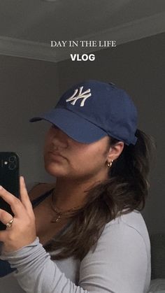 a woman in a baseball cap taking a selfie with her cell phone