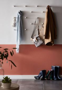 a pair of rain boots hanging on the wall next to a potted plant and coat rack