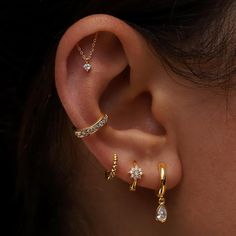 a woman wearing three different types of ear piercings on her left ear and the other one has a diamond set in it