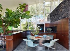 a kitchen with a table and chairs near a tree in the middle of the room