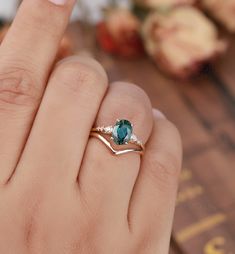 a close up of a person's hand holding a ring with a blue stone