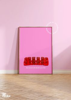 a pink wall with three red gummy bears on it in front of a wooden frame