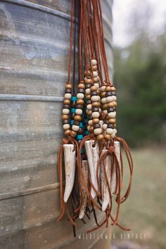 a bunch of beads hanging from the side of a barrel with some feathers attached to it