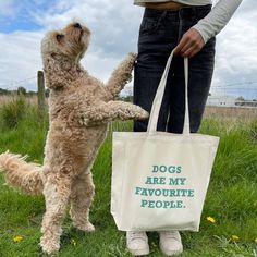 a dog standing on its hind legs holding onto a bag that says dogs are my favorite people