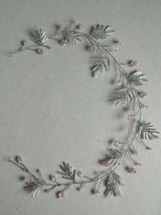 an image of a wreath made out of silver beads and leaves on a white background