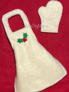 a white oven mitt with holly applique on it and a red background