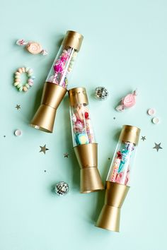 three gold tubes filled with candy sitting on top of a blue surface