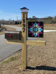 a mailbox with a quilt on it is next to a rural road and grassy area