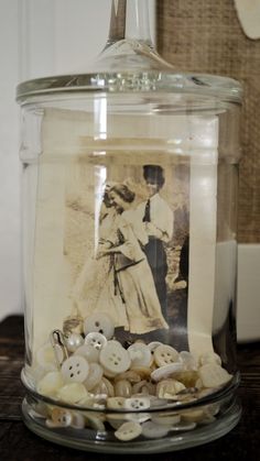 a glass jar filled with buttons on top of a table