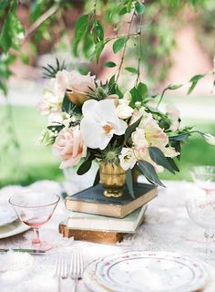 a table topped with books and flowers next to a vase filled with white flowers on top of a table