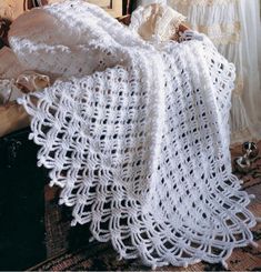 a white crocheted blanket sitting on top of a bed next to a window